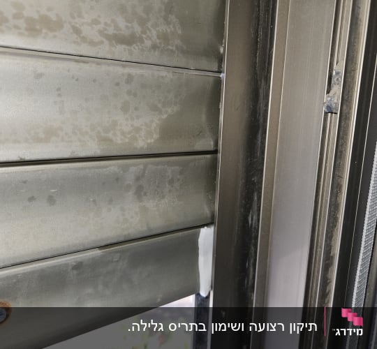 תריס מתכת עם כתמי חלודה וברגים
